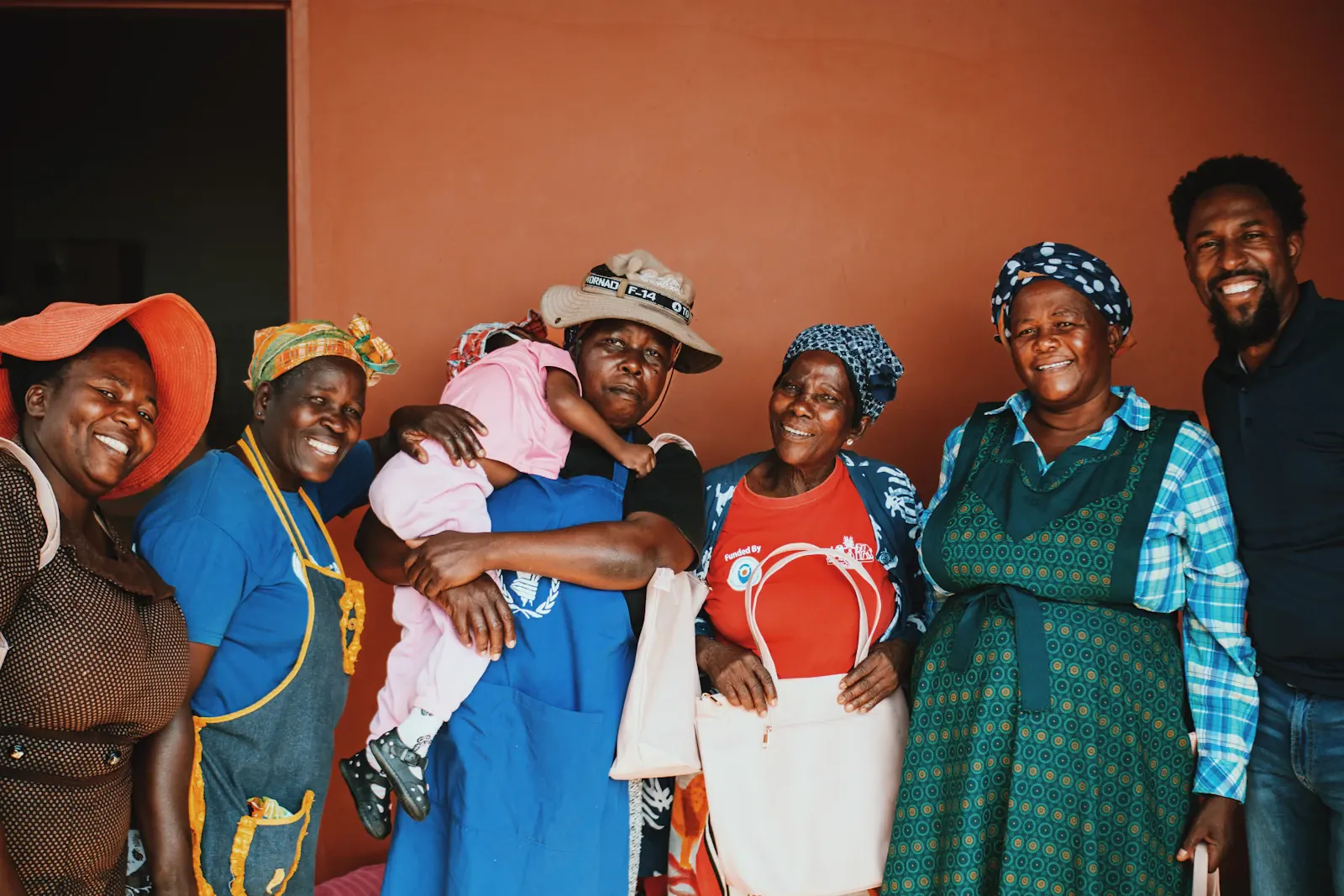 Un groupe de femmes et un homme sourient, réunis autour d’un enfant.